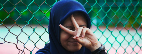 Foto kvinde med slør smiler og holder en hånd med v-tegn op foran ansigtet